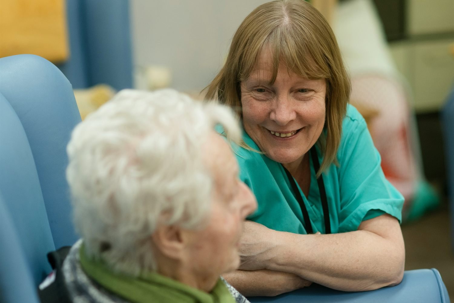 A nurse leaning in to speak warmly with an older patient